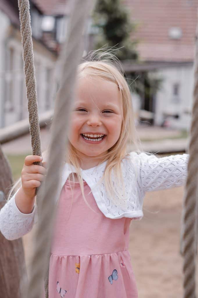Kindergartenfotos im freien Spiel in der Kita in Hamburg lachendes Mädchen
